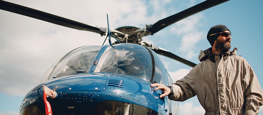 A male pilot standing next to a helicopter